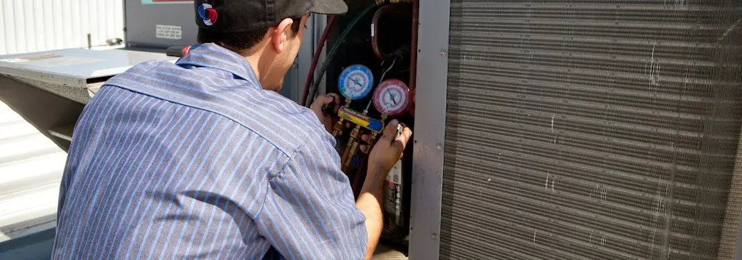 HVAC technician servicing a condenser unit in Shelley
